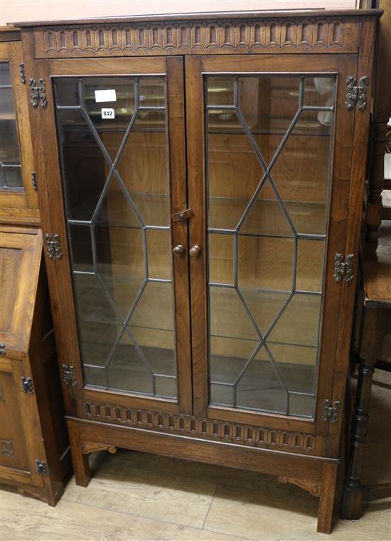 A carved oak two door glazed leaded cabinet W.81cm